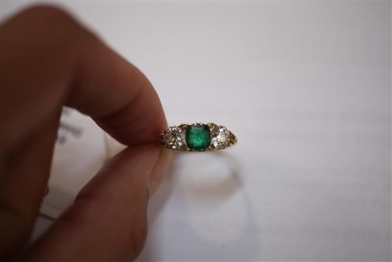 An 18ct gold and three stone emerald and diamond ring, size N.